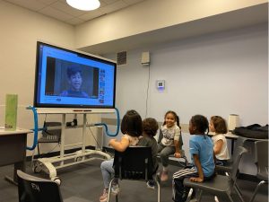 Children watch a clip from Sesame Street on a smartboard