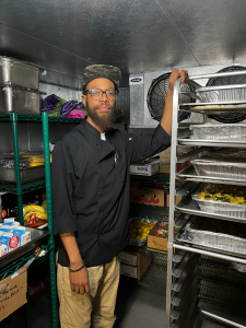 Damien stands inside the kitchen's walk-in fridge.