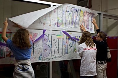 Volunteers hang birthday banner