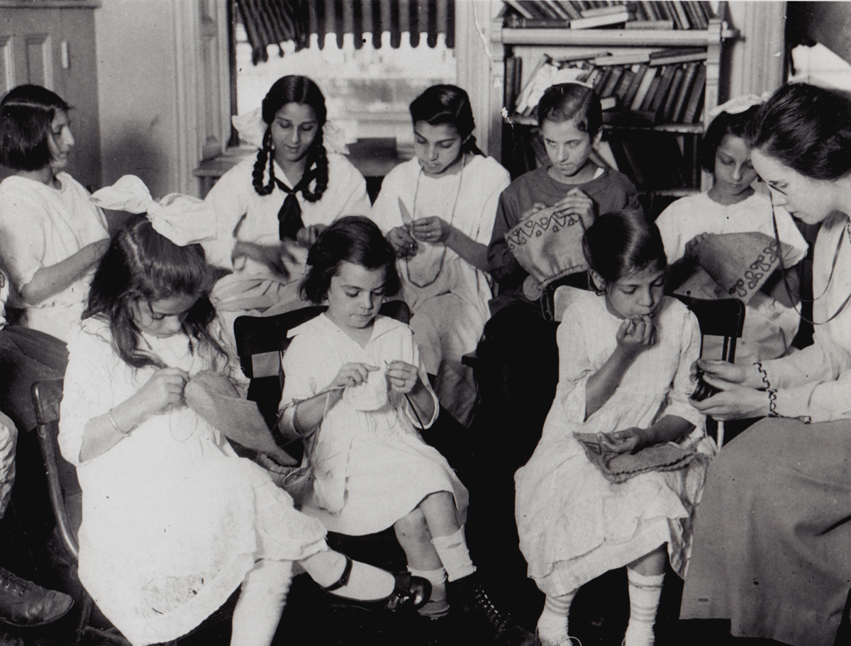Historic photo of children taking a sewing class at Henry Street, circa early 1900s