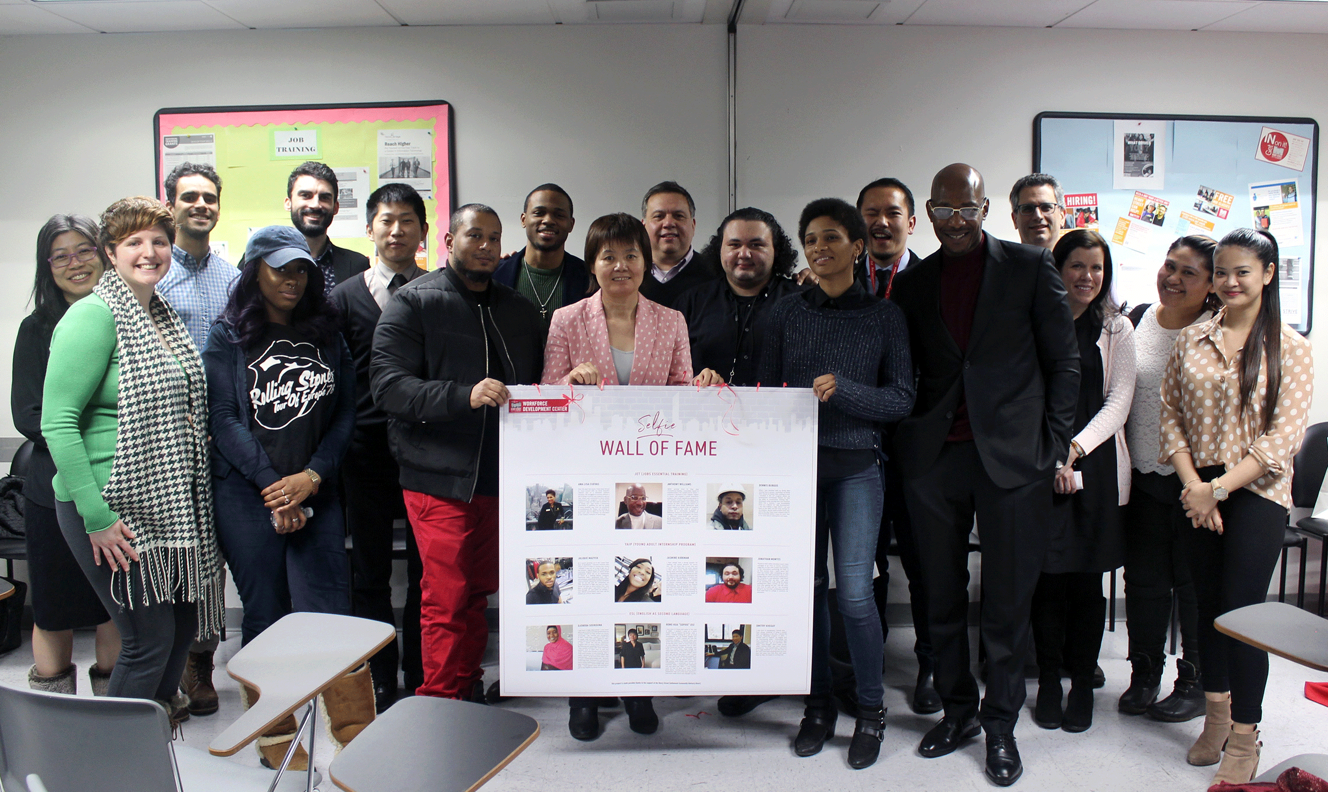 Group of students and staff smile with Wall of Fame poster, highlighting employment success