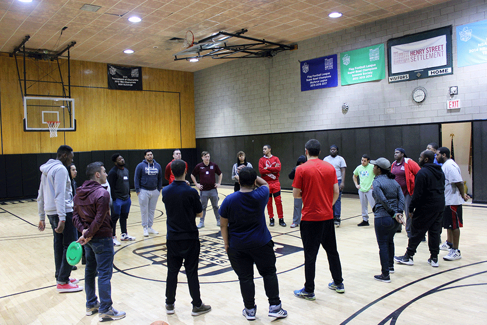 Young adults stand in circle at basketball court in gym