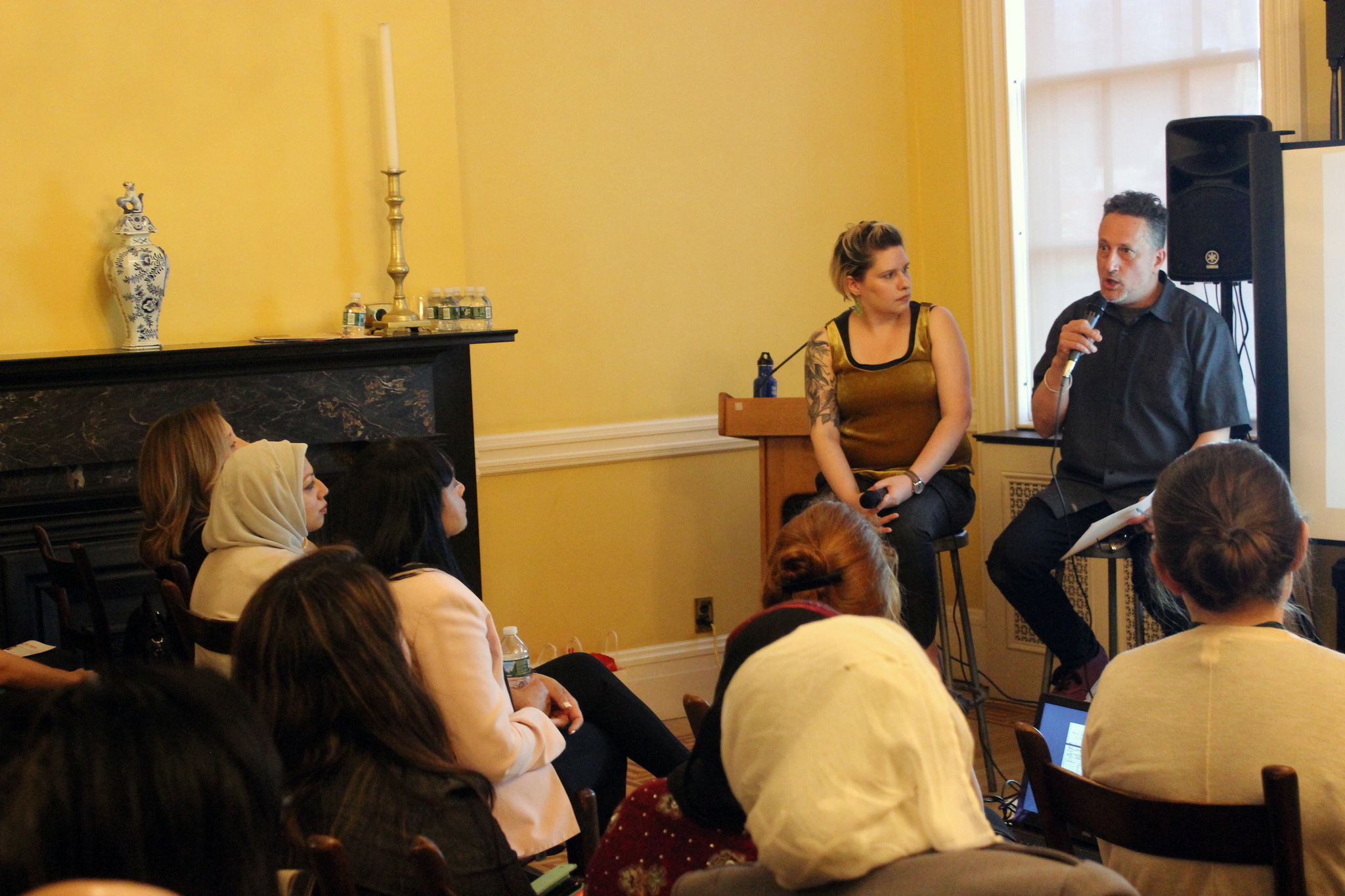 A woman and a man address an audience at Henry Street Settlement