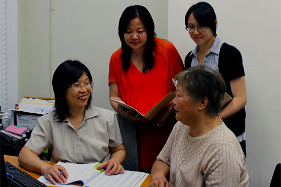 Three women helping another woman with paperwork needed to sign up for health insurance