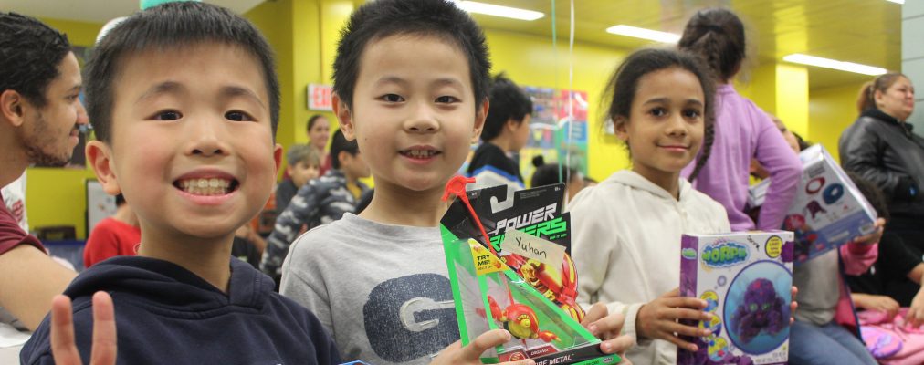 Children smiling holding up toys