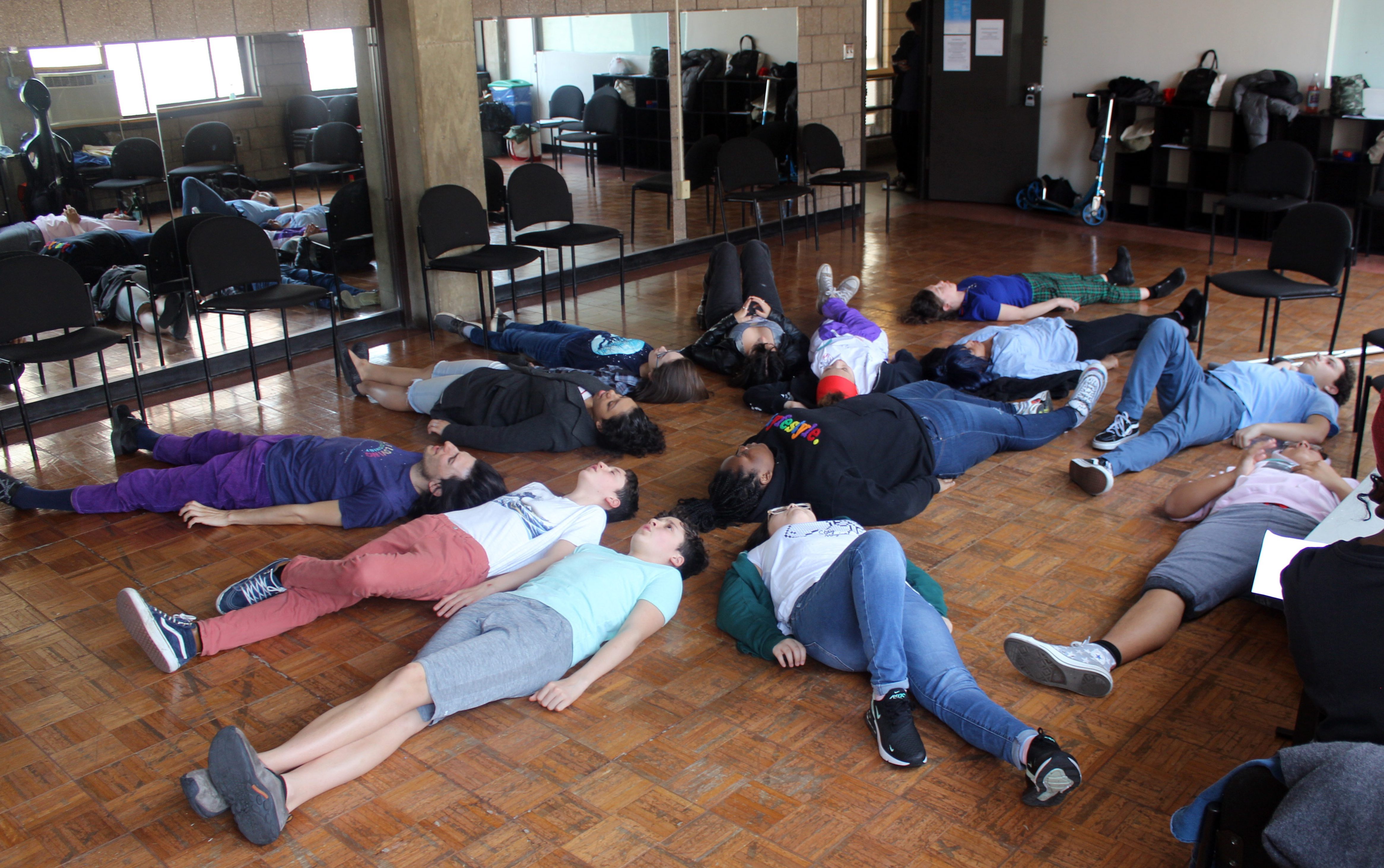 Group class lies down on studio floor in circle at Abrons Arts Center