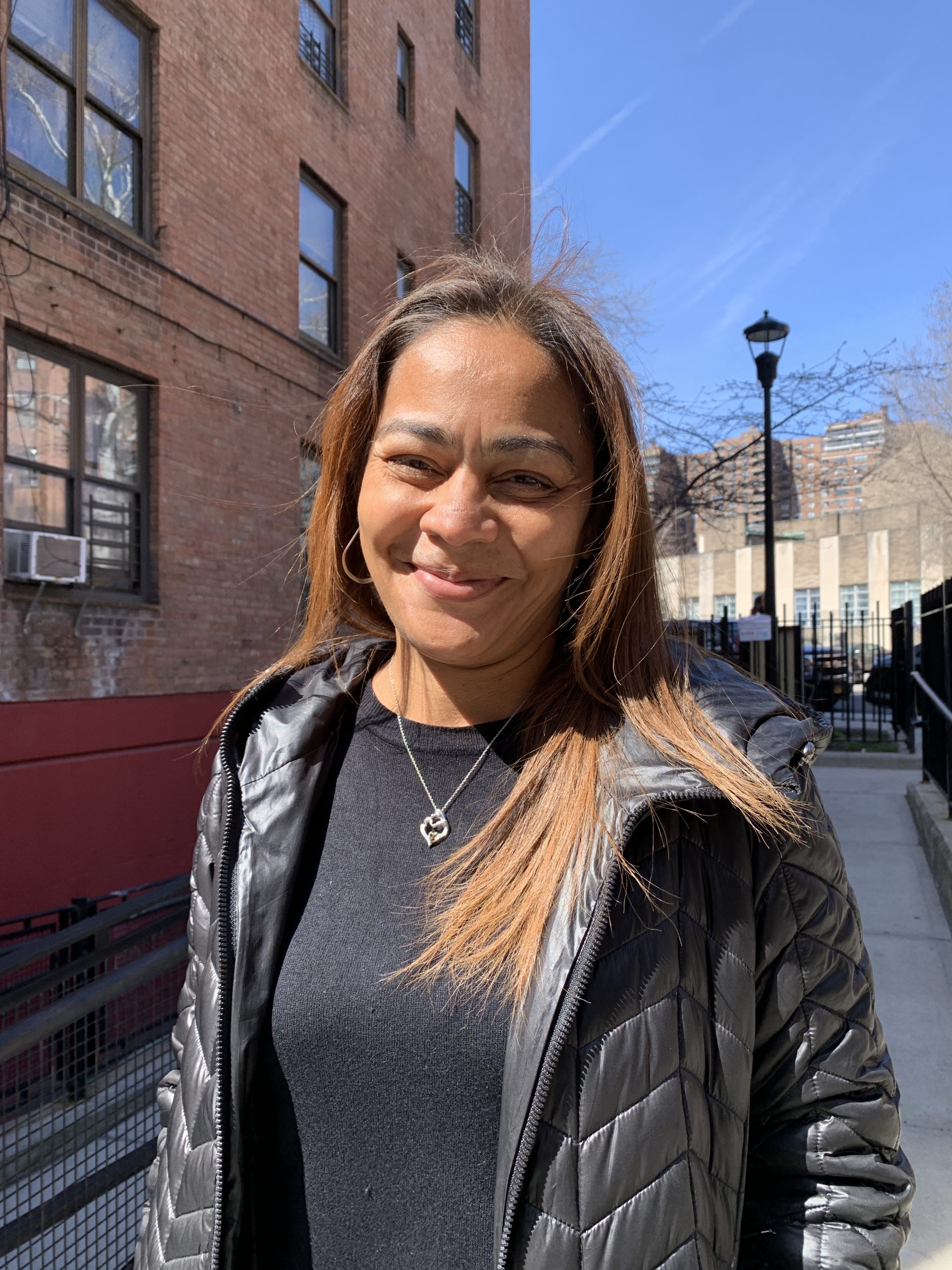 Woman smiles and stands in front of building