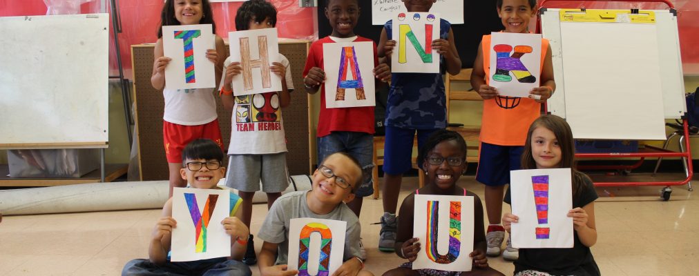 Children holding letters that spell out 