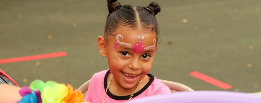 Young child with face paint smiles at camera