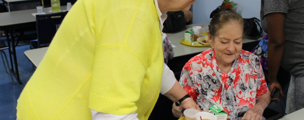 Woman placing food on table for Older Adult Center participant