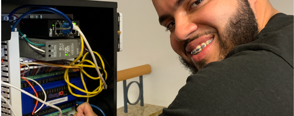 Young man smiles while working on internal building system