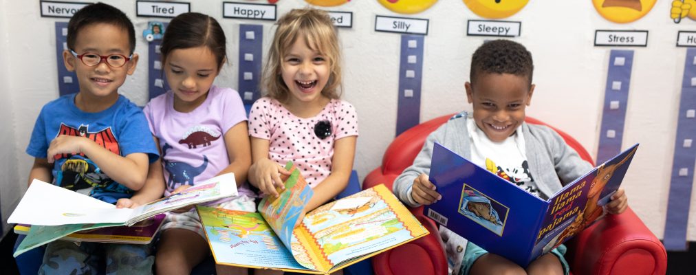 4 Young students posing together, smiling with books