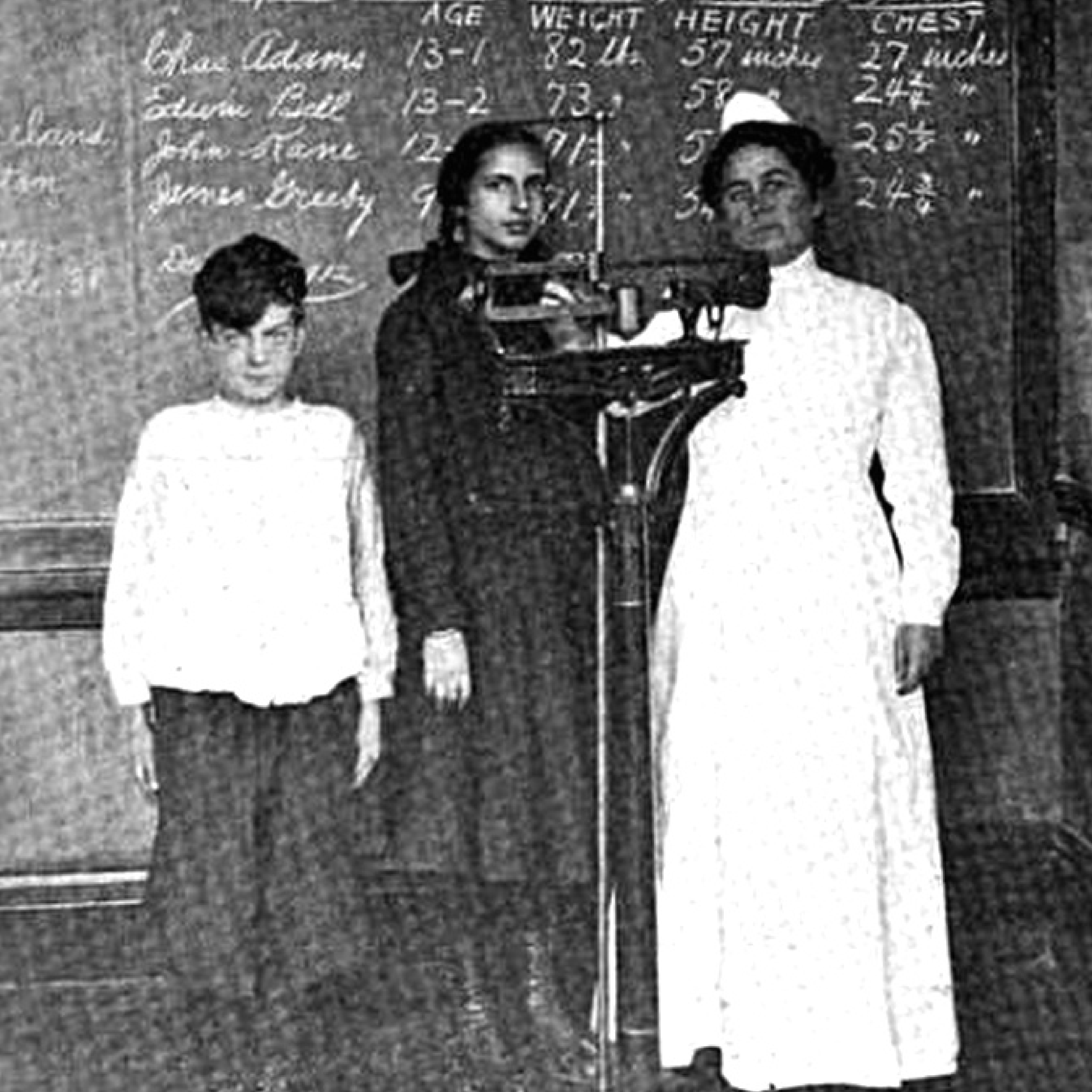 Vintage photo of nurse and children posing in front of a chalkboard