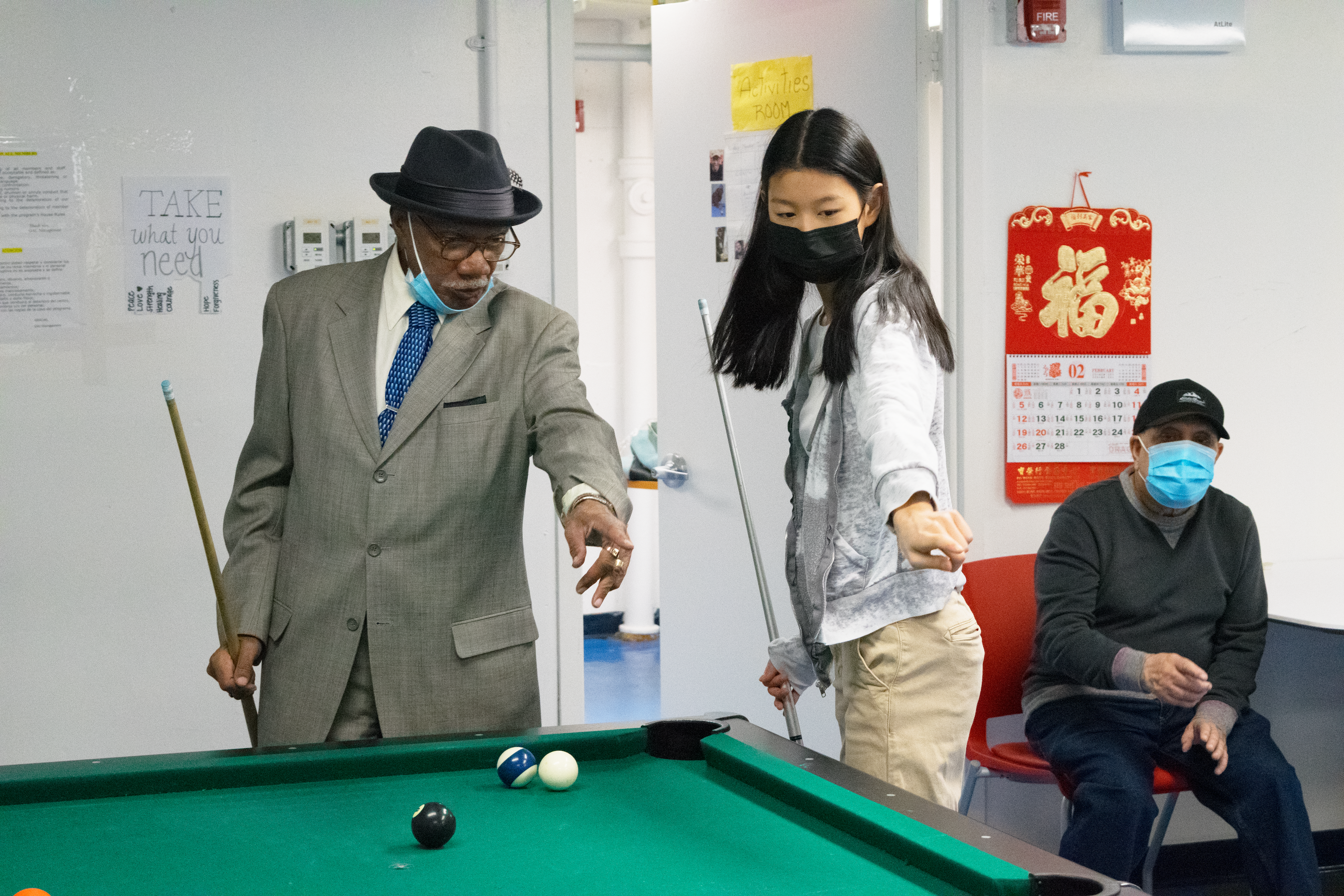 A teen volunteer plays pool with a member of the Henry Street Settlement Older Adult Center