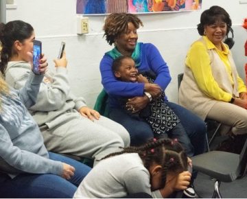 An older adult mentor hugs a preschooler mentee