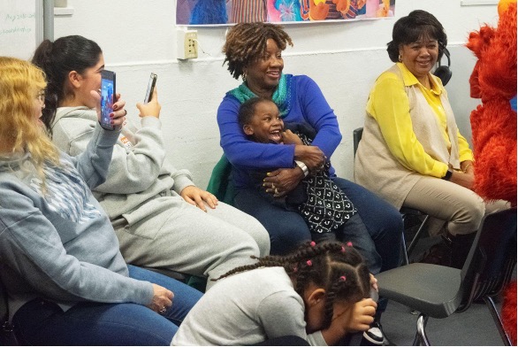 An older adult mentor hugs a preschooler mentee