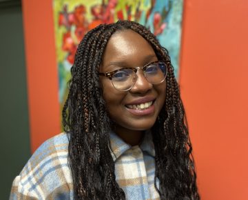 A Black woman with long braided hair and glasses