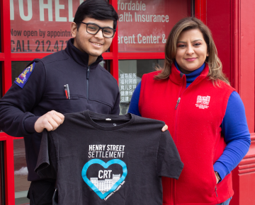 A young man in an EMT uniform holds up a t-shirt that says, 